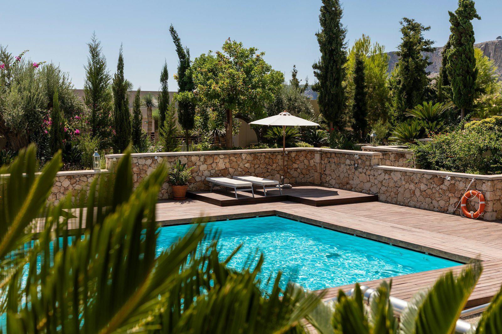 Piscine privée entourée de murs en pierre et de verdure